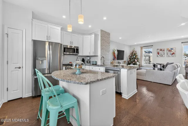 a kitchen with stainless steel appliances granite countertop a table chairs refrigerator and a sink