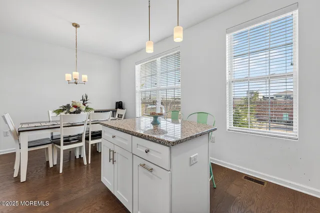 a kitchen with stainless steel appliances granite countertop a stove a chimney a sink and a dining table