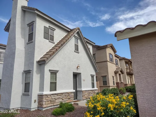 a view of a white house with potted plants and a yard