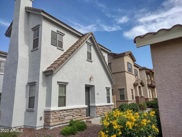 a view of a white house with potted plants and a yard