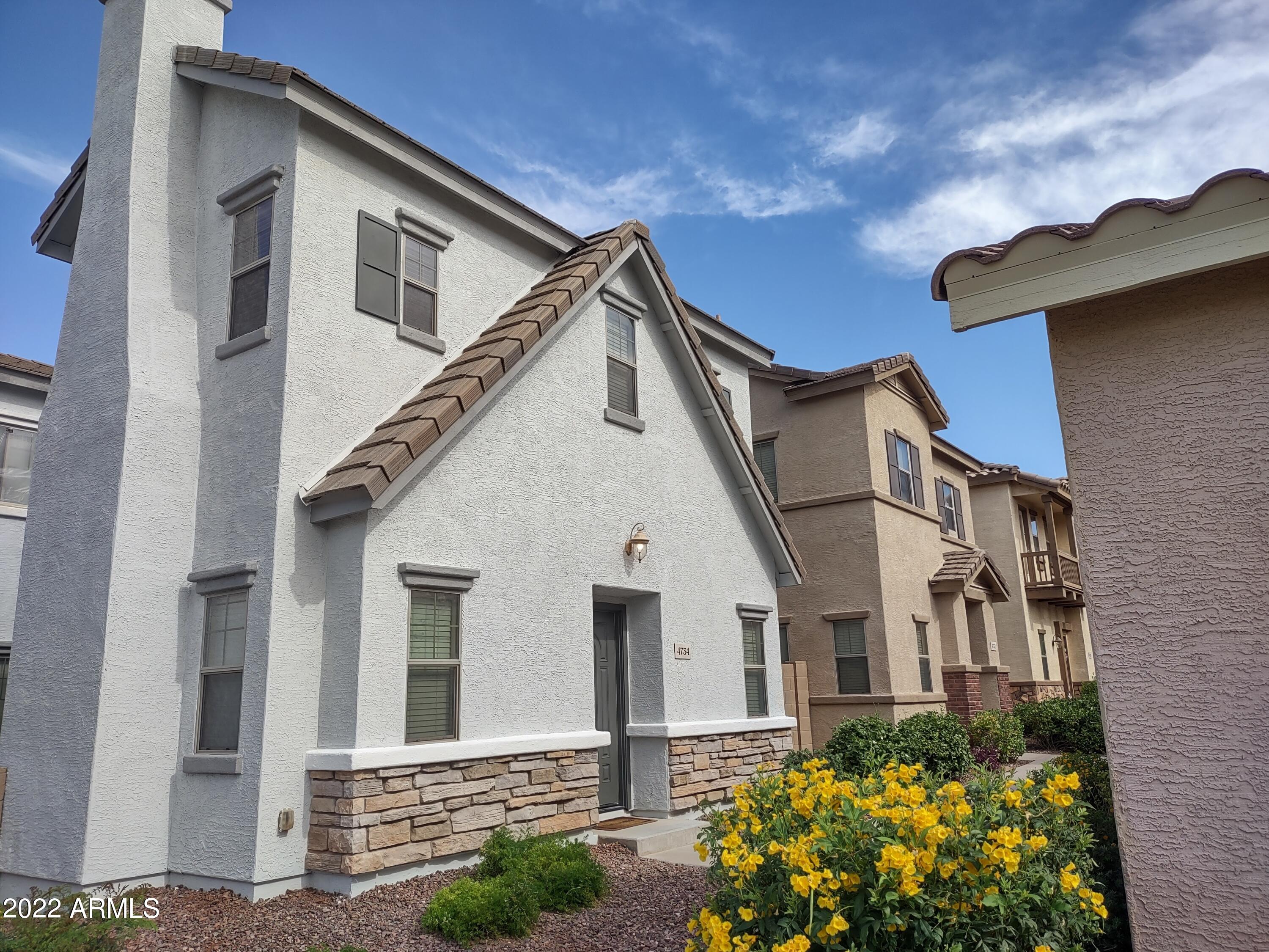 4734 East Olney Avenue Gilbert, AZ 85234 - Photo 1 of 26 a view of a white house with potted plants and a yard
