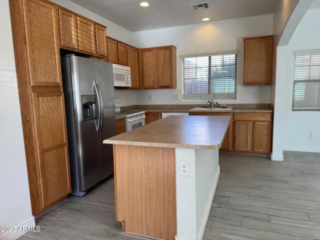 a kitchen with stainless steel appliances a refrigerator a sink a stove a microwave and wooden floors