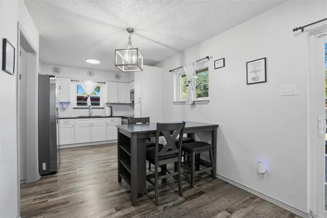 a kitchen with stainless steel appliances granite countertop a dining table chairs refrigerator and cabinets