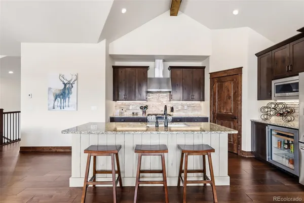 a kitchen with granite countertop a stove a sink and a refrigerator