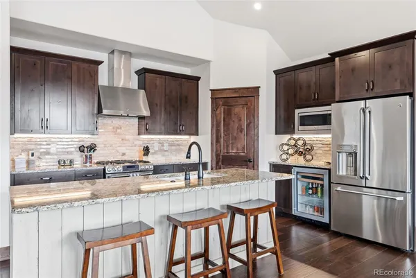 a kitchen with stainless steel appliances granite countertop a table chairs microwave and refrigerator