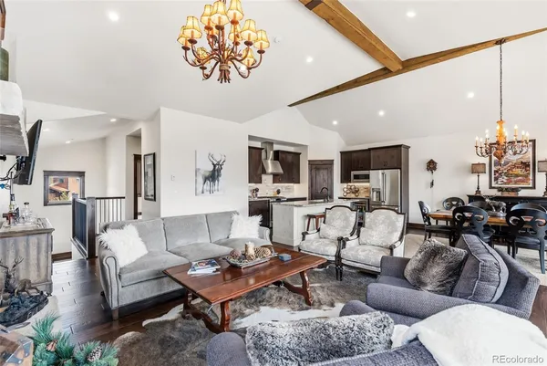 a living room with furniture potted plant and open kitchen view