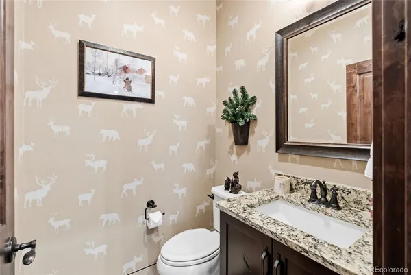 a bathroom with a granite countertop sink a toilet and a mirror