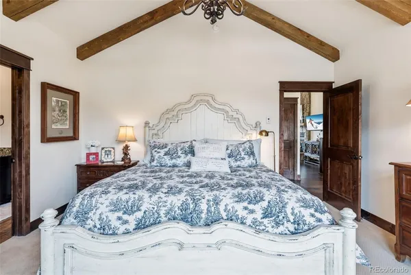 a large bed sitting in a bedroom next to a lamp on a table and a chandelier