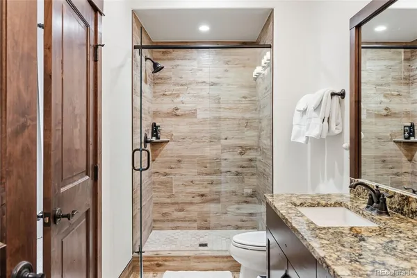 a bathroom with a granite countertop sink toilet and shower
