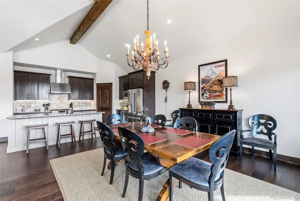 a dining room with wooden floor a chandelier a wooden table and chairs