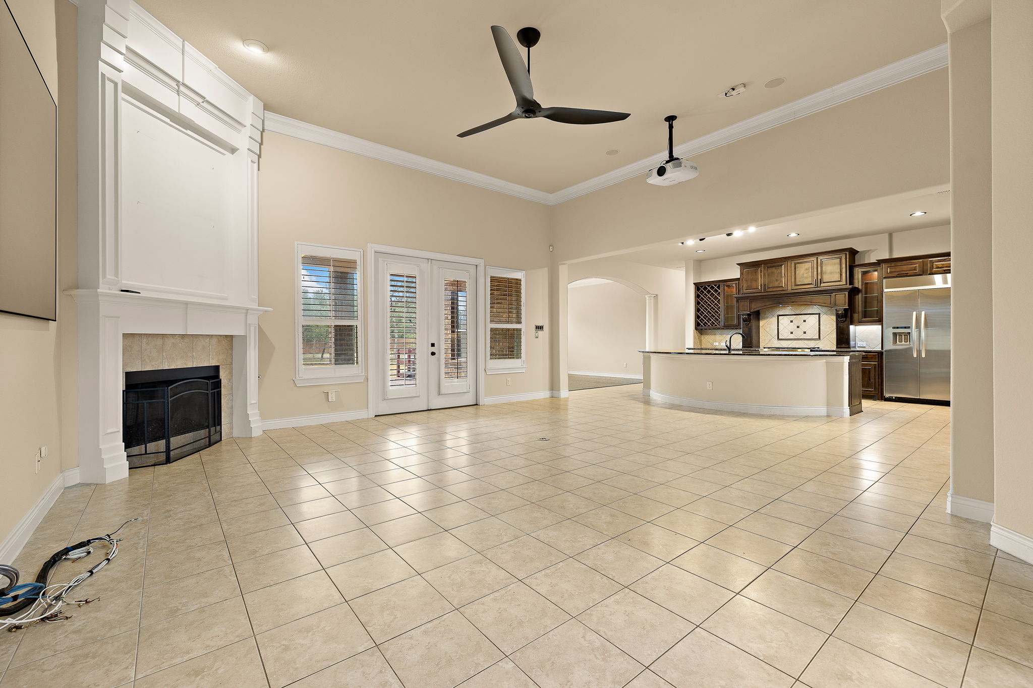 174 Estrella Crossing Georgetown, TX 78628 - Photo 8 of 38 Unfurnished living room with arched walkways, light tile patterned floors, crown molding, a tiled fireplace, and french doors