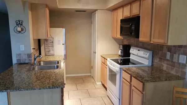 a kitchen with granite countertop a sink and a refrigerator