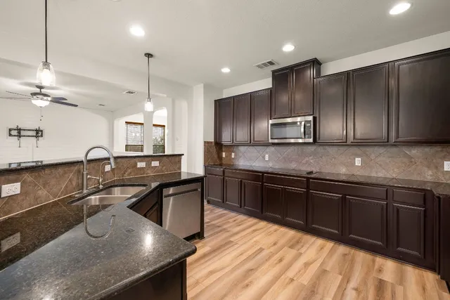 a kitchen with kitchen island granite countertop a sink stainless steel appliances and cabinets