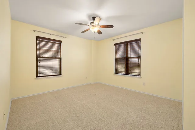 an empty room with windows and ceiling fan