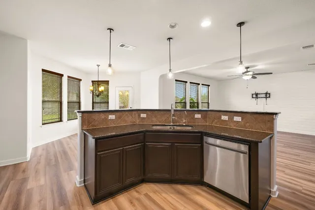 a kitchen with stainless steel appliances granite countertop a sink a stove and a wooden floors