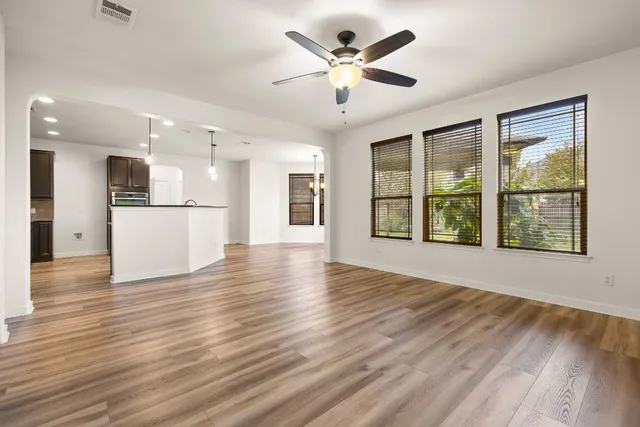 a view of an empty room with a kitchen and wooden floor