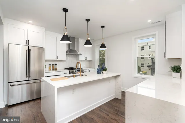 a kitchen with stainless steel appliances granite countertop a sink a refrigerator a stove a kitchen island with wooden floor