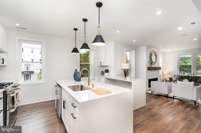 a large white kitchen with sink a center island and stainless steel appliances
