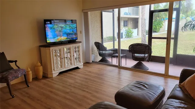 a living room with furniture and a flat screen tv next to a large window