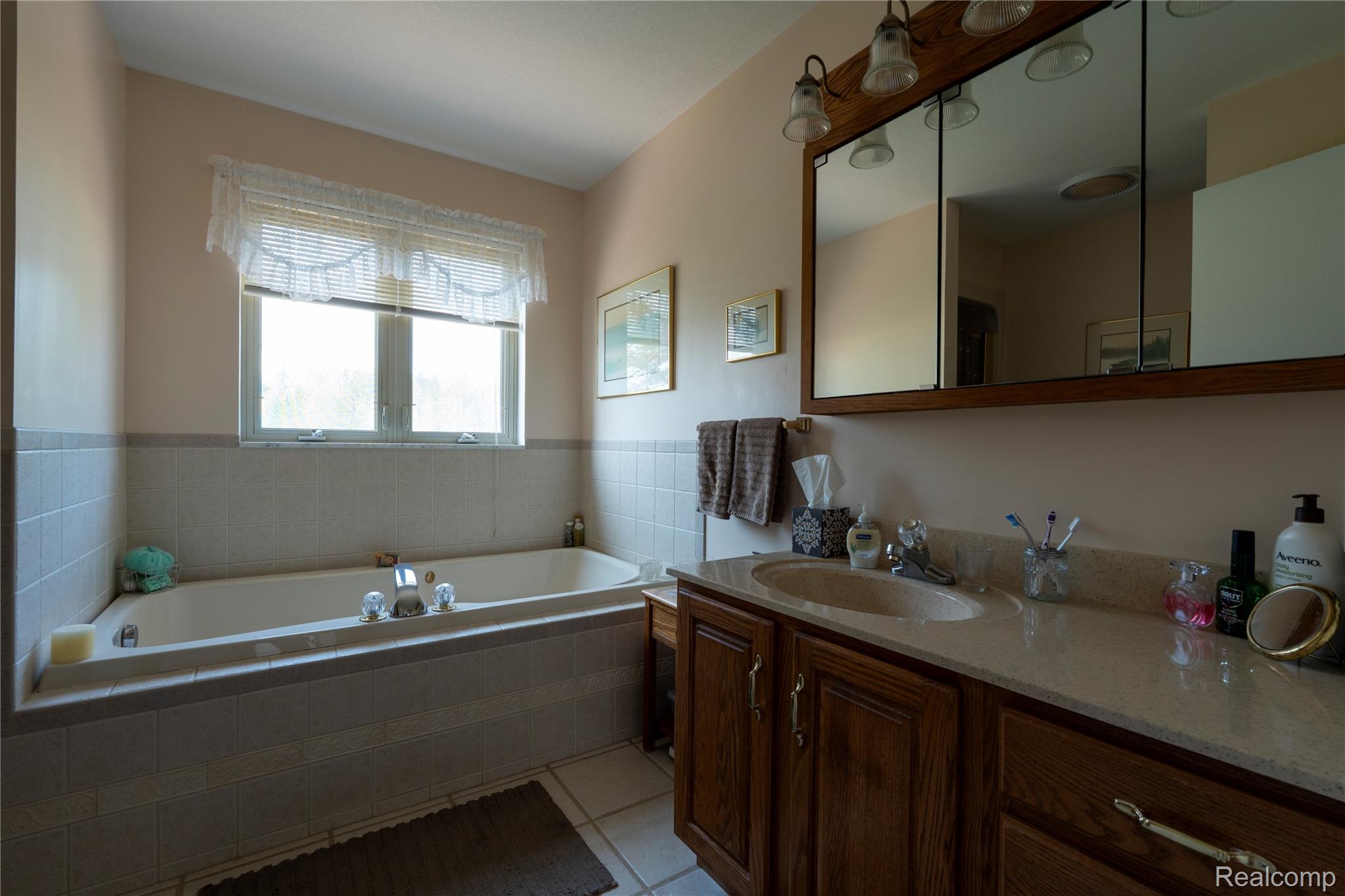 4180 Sage Lake Road Lupton, MI 48635 - Photo 23 of 40 Bathroom with vanity, a bath, and light tile patterned floors