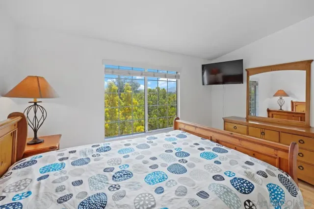 a bedroom with a bed and a flat tv screen on dresser