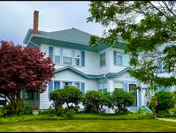 a front view of a house with a yard and potted plants