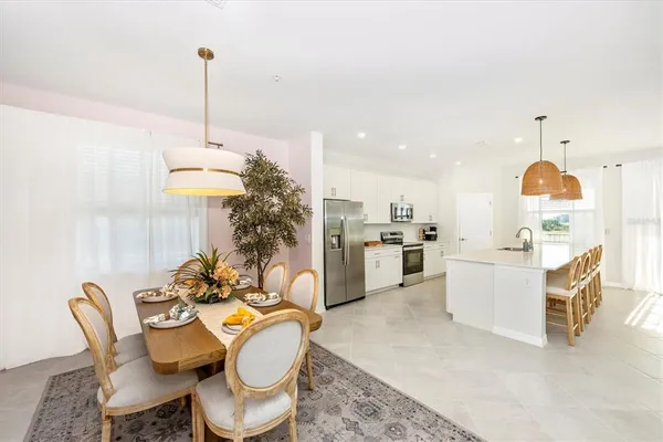 a kitchen with stainless steel appliances a dining table chairs a sink and a refrigerator