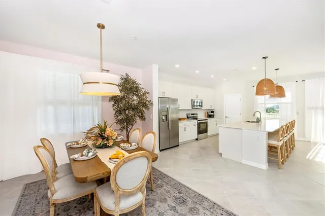 a kitchen with stainless steel appliances a dining table chairs a sink and a refrigerator