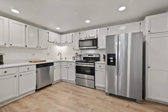 a kitchen with cabinets stainless steel appliances and a window