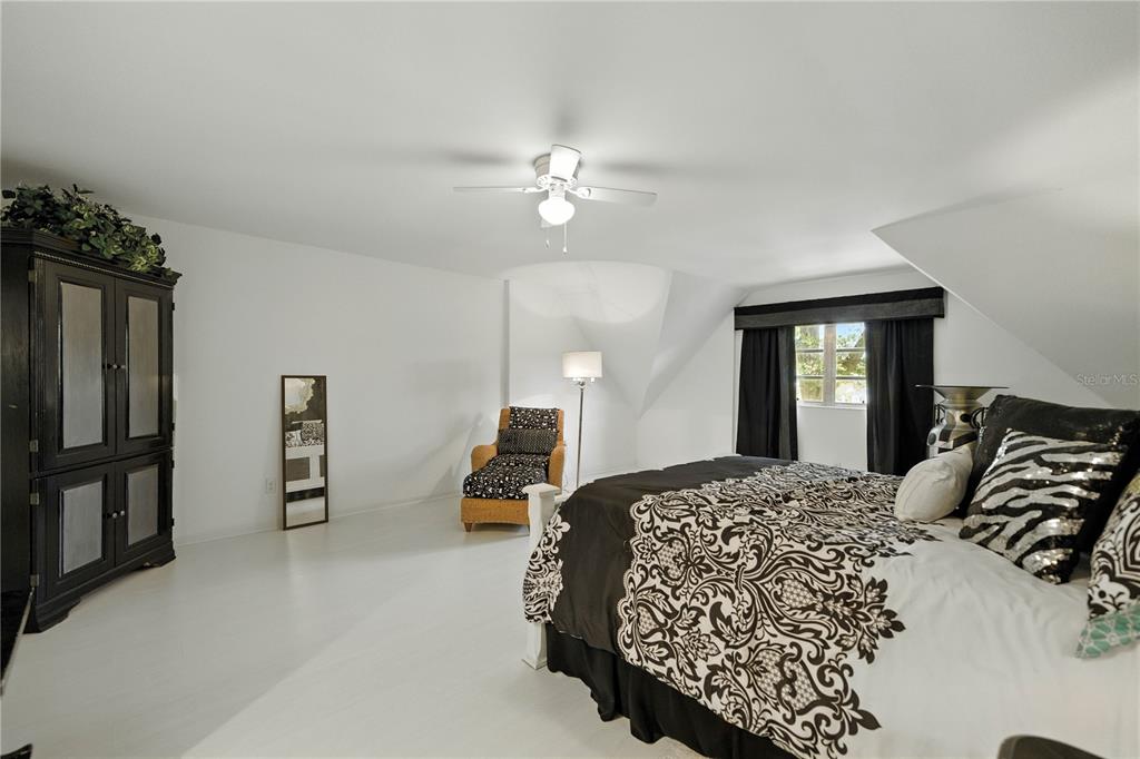 9951 Southwest 88th Court Road, Unit B Ocala, FL 34481 - Photo 16 of 29 a bedroom with a large bed and a chandelier