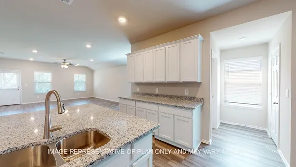 a kitchen with kitchen island granite countertop a sink and a stove top oven with wooden floor