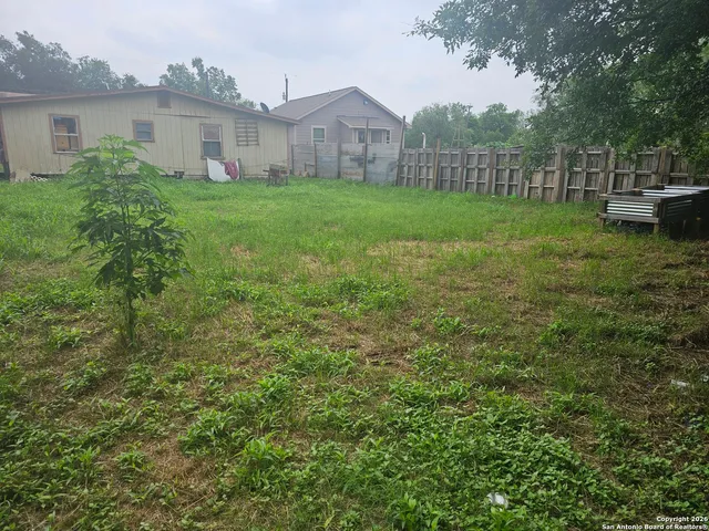 a view of a backyard with plants and wooden fence