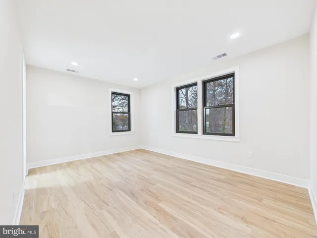 a large kitchen with kitchen island a stove a sink dishwasher a refrigerator and white cabinets with wooden floor