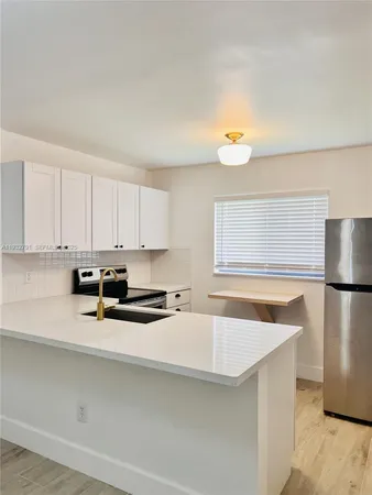 a kitchen with stainless steel appliances a refrigerator a sink and white cabinets