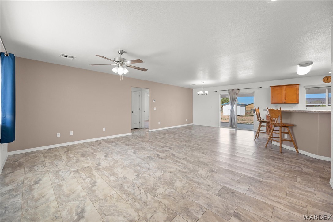 3411 West Carmichael Road Golden Valley, AZ 86413 - Photo 14 of 97 Unfurnished living room with suspended lighting and a ceiling fan