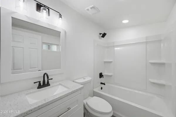 a bathroom with a bathtub shower sink vanity mirror and toilet