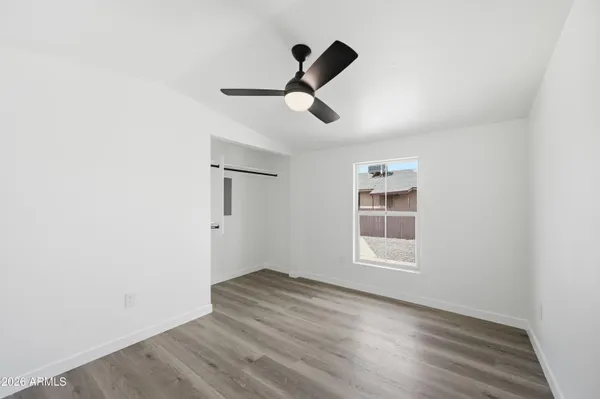 a view of empty room with wooden floor and ceiling fan