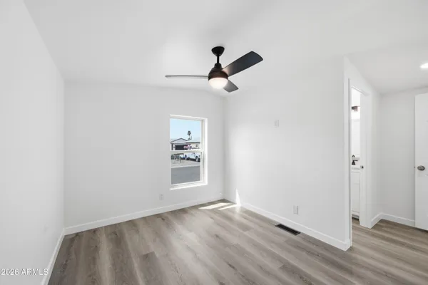 an empty room with wooden floor ceiling fan and windows