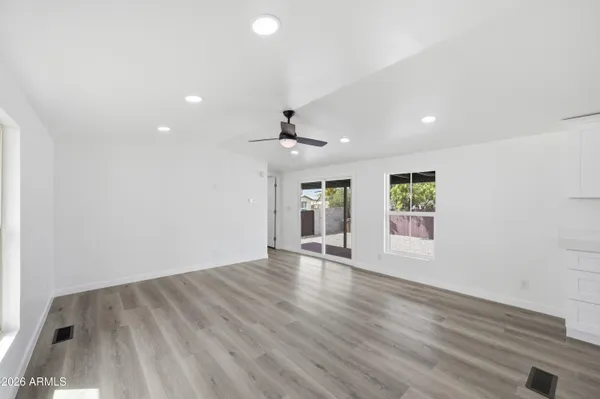 an empty room with wooden floor and windows