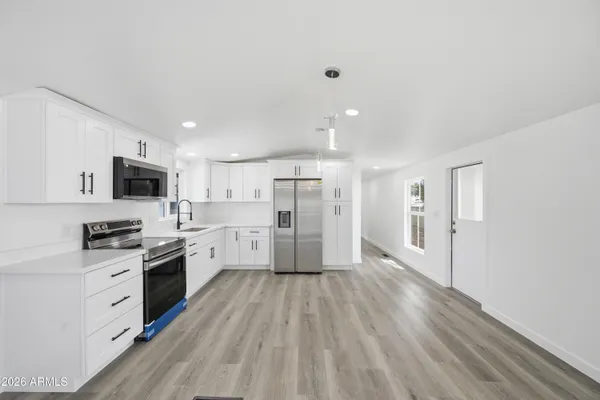 a large kitchen with cabinets wooden floor and stainless steel appliances