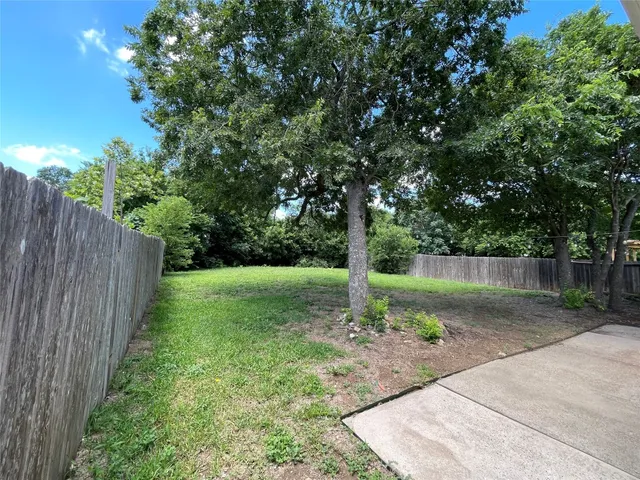 a backyard of a house with lots of plants and tree