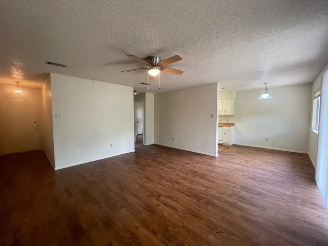 an empty room with wooden floor and a ceiling fan