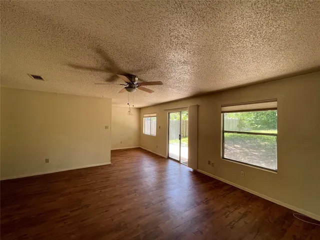 a view of an empty room with a window and wooden floor
