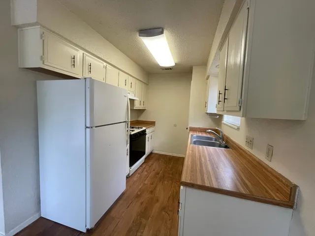 a kitchen with stainless steel appliances granite countertop a refrigerator a stove and a sink