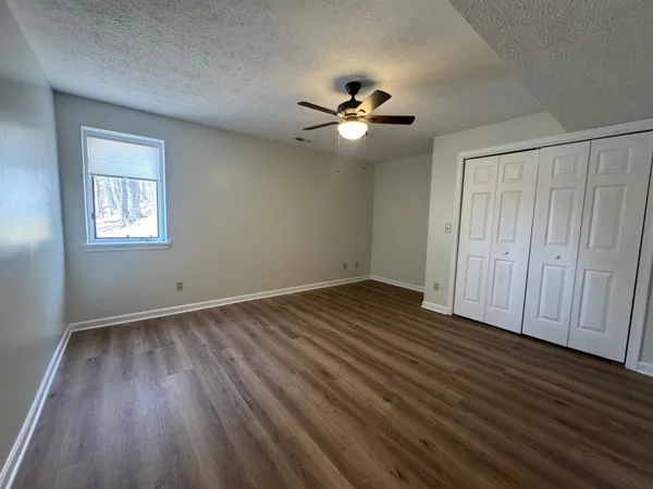 a view of empty room with wooden floor and fan