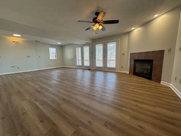an empty room with wooden floor fireplace and windows