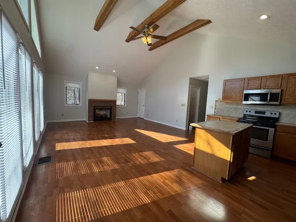 a kitchen with granite countertop a stove top oven a sink dishwasher a refrigerator and a fireplace with wooden floor