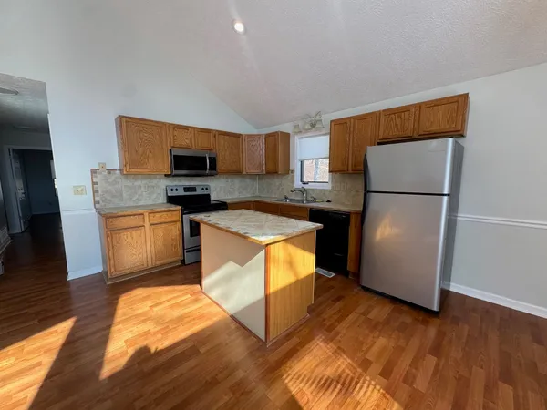 a kitchen with stainless steel appliances granite countertop a refrigerator a stove a sink and a microwave