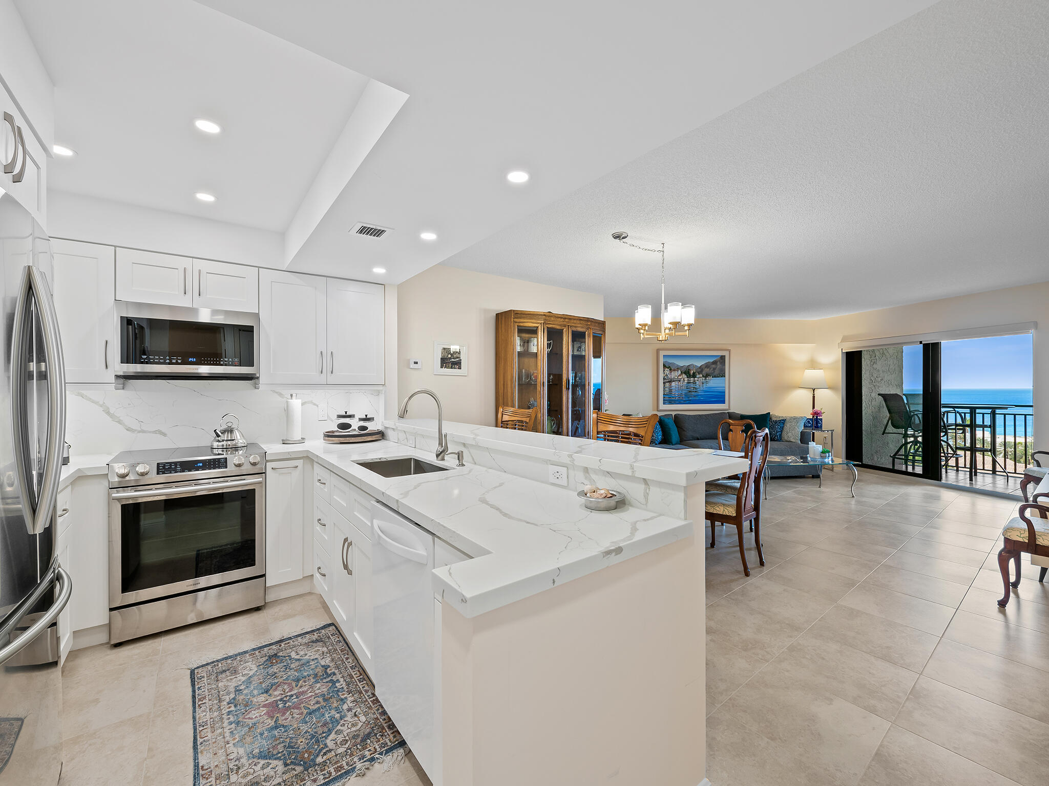 a large white kitchen with stainless steel appliances lots of counter top space and furniture