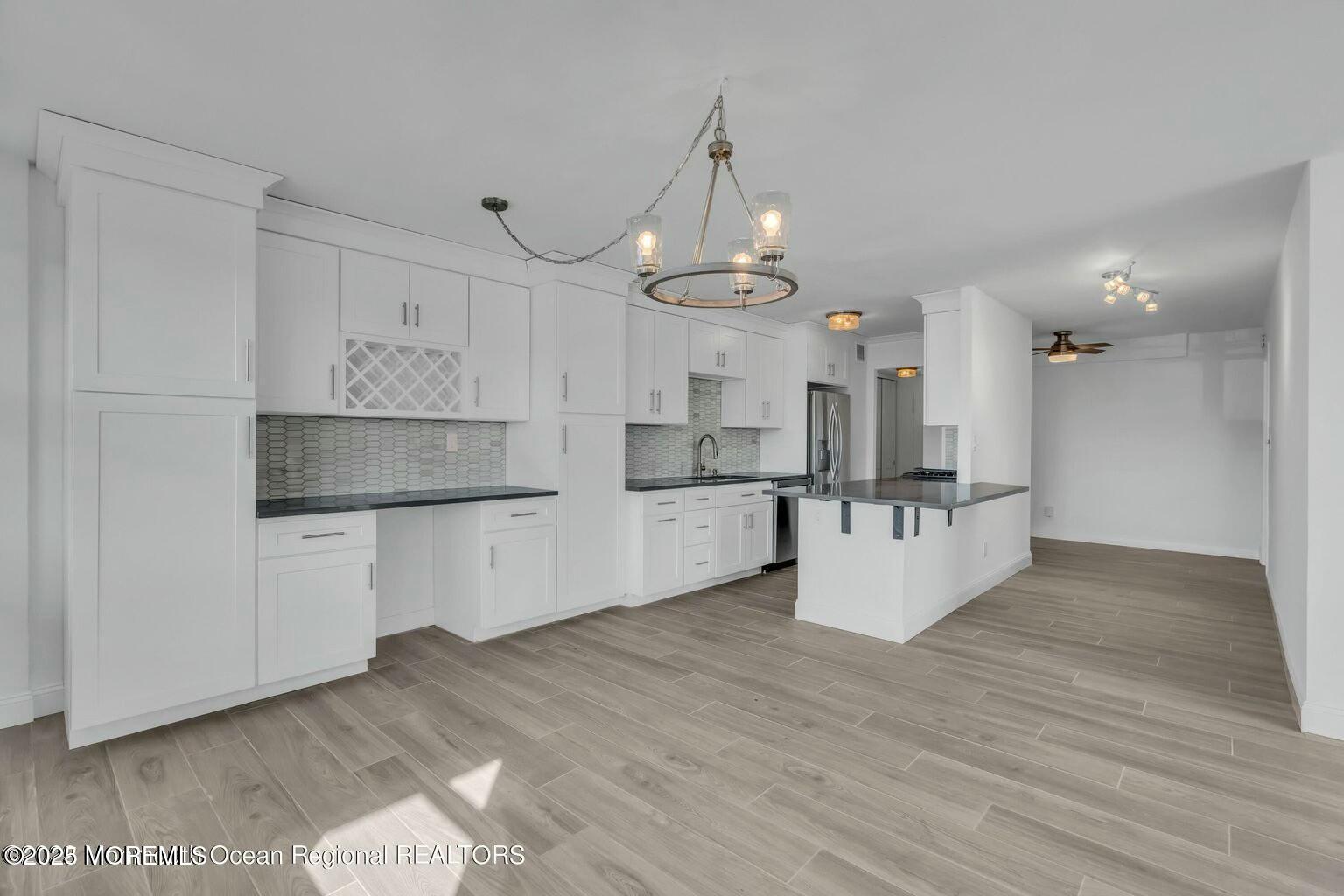 28 Riverside Avenue, Unit 1G Red Bank, NJ 07701 - Photo 3 of 25 a large kitchen with kitchen island a refrigerator a stove a sink dishwasher and white cabinets with wooden floor